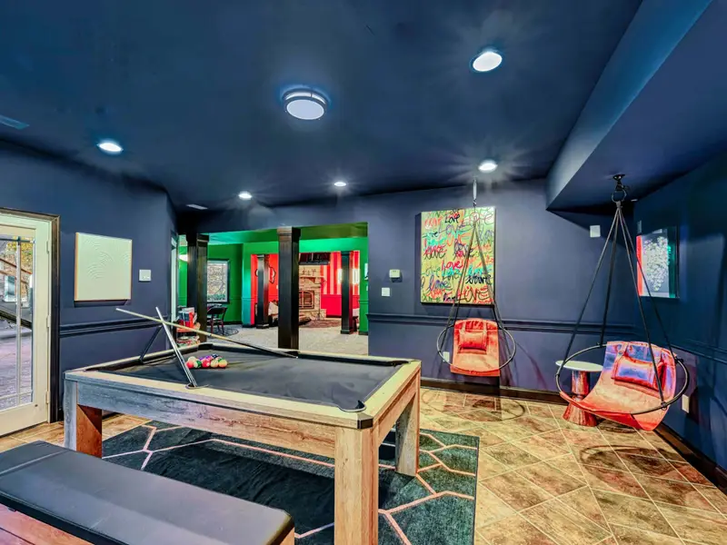 The Billiard & Games Lounge is a lower-level play hub with a convertible pool/ping-pong/dining table, darts, arcade and wall games, leather swings, and direct patio access—designed for laughter, competition, and all-ages fun.