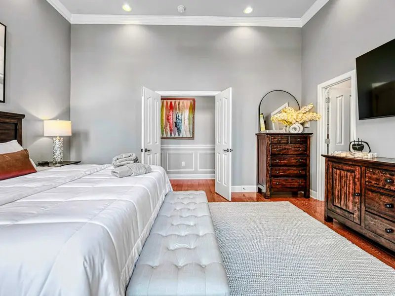 The Primary Suite is a private retreat with a king bed dressed in hotel-quality linens, floor-to-ceiling windows with serene views, automatic shades, a 65” Smart TV, walk-in closet, and French doors to the deck—designed for deep rest and unhurried la