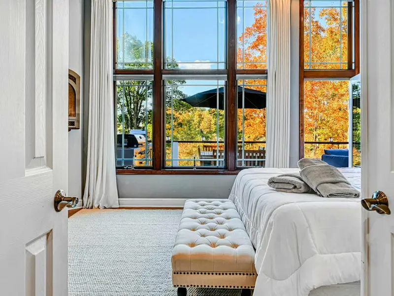 The Primary Suite is a private retreat with a king bed dressed in hotel-quality linens, floor-to-ceiling windows with serene views, automatic shades, a 65” Smart TV, walk-in closet, and French doors to the deck—designed for deep rest and unhurried la