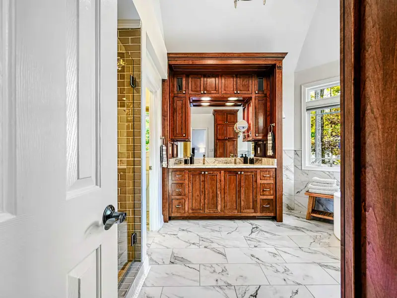 The Primary Ensuite is a spa-like retreat featuring a soaking tub with lake views, arched windows, and an oversized walk-in shower with dual heads and bench—designed for quiet mornings, slow evenings, and total relaxation.