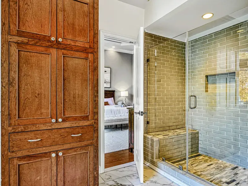 The Primary Ensuite is a spa-like retreat featuring a soaking tub with lake views, arched windows, and an oversized walk-in shower with dual heads and bench—designed for quiet mornings, slow evenings, and total relaxation.
