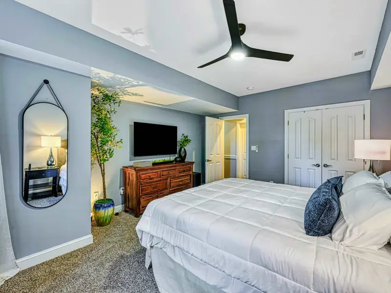 King Bedroom: Soft blue-gray retreat with plush king bed, luxury linens, smart TV, ceiling fan, roomy closet, cozy window seating, and access to a shared hall bathroom.