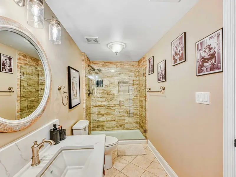 Walk-in glass shower, marble-style vanity, stocked dispensers, bright lighting, ample storage, and a convenient urinal—designed for comfort and ease just outside the bedrooms.