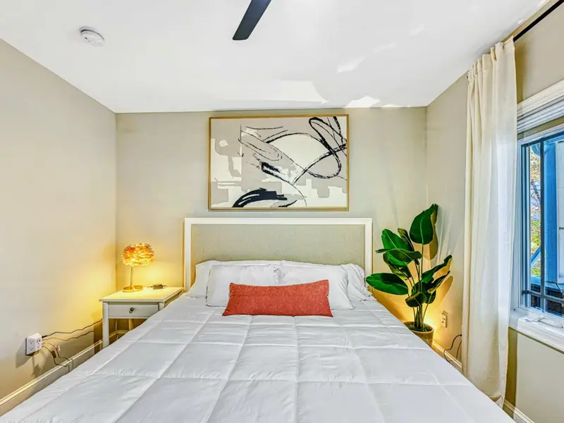 King Suite: Warm, serene retreat with king bed, hotel-quality linens, smart TV, bedside charging, soft lighting & greenery, plus access to a shared hall bathroom.