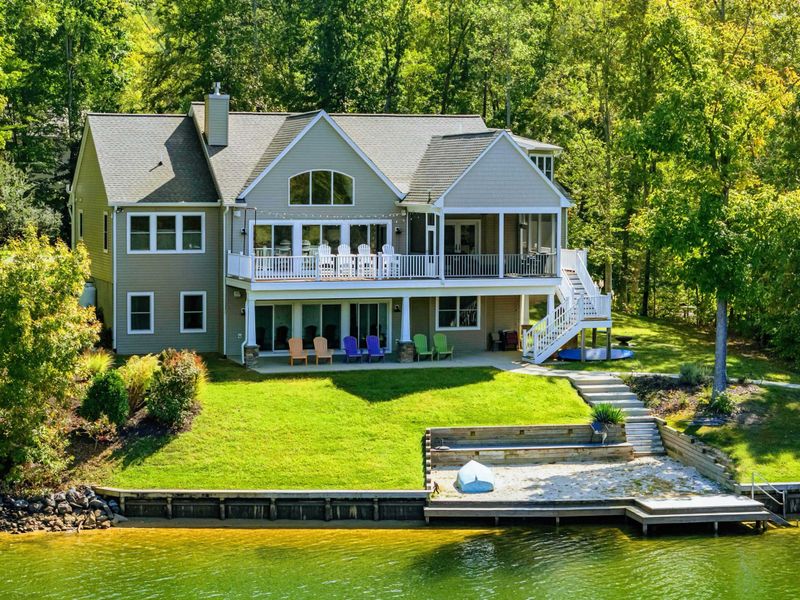 Exterior - The craftsman home from the water, tiered decks and colorful Adirondacks above a sweeping lawn that rolls down to the private dock.