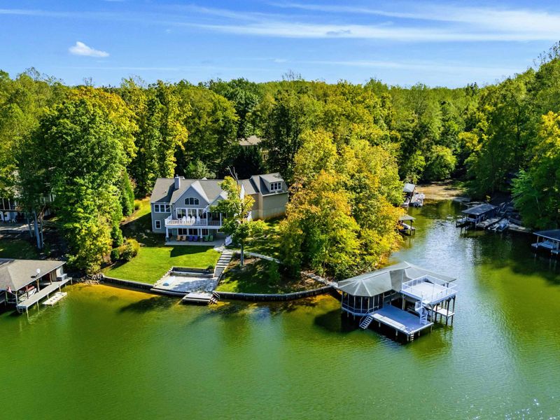 Aerial View - The home, manicured yard, and two-story dock seen from above the lake.