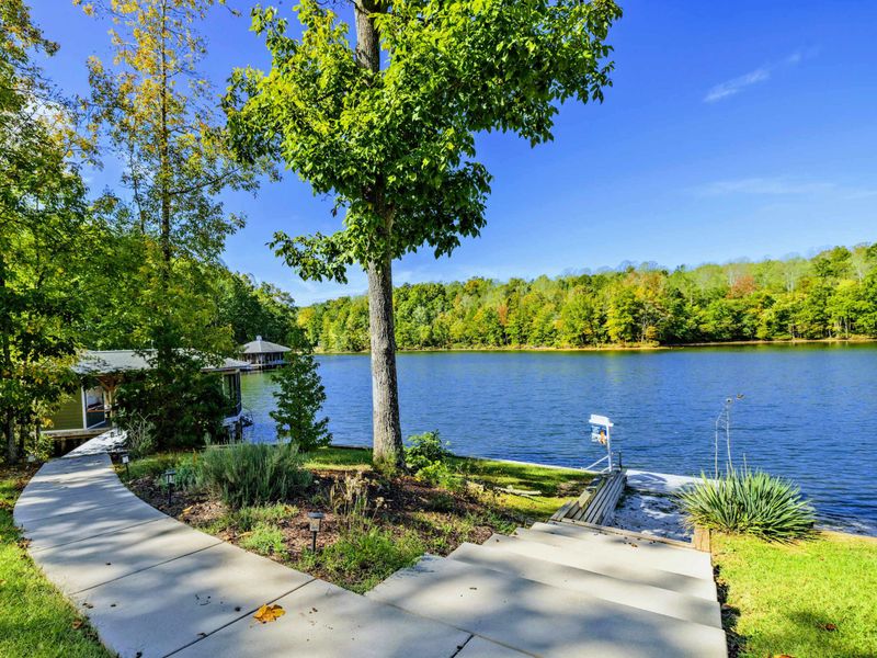Lakeside Walkway - Paved path winds along the waterfront with the dock and boathouse just beyond.