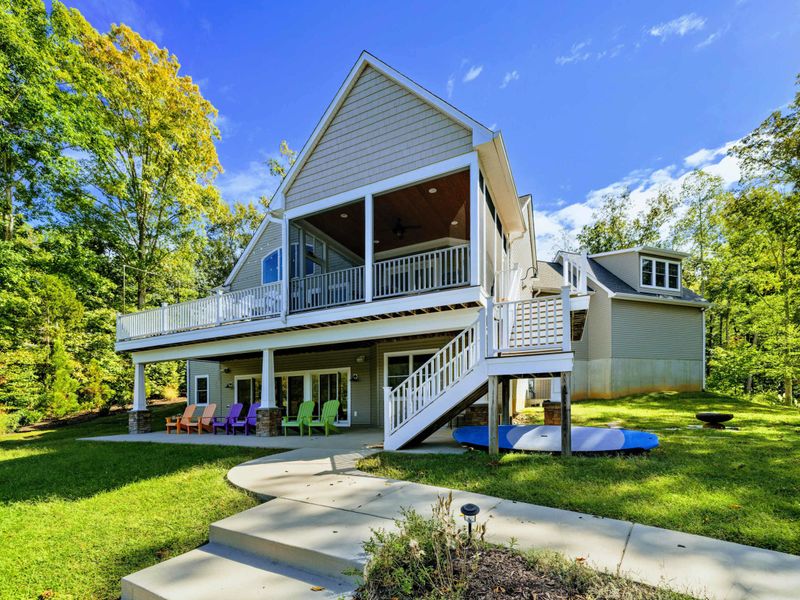 Rear Exterior - A-frame roofline with screened porch above and colorful Adirondack chairs on the lower patio.