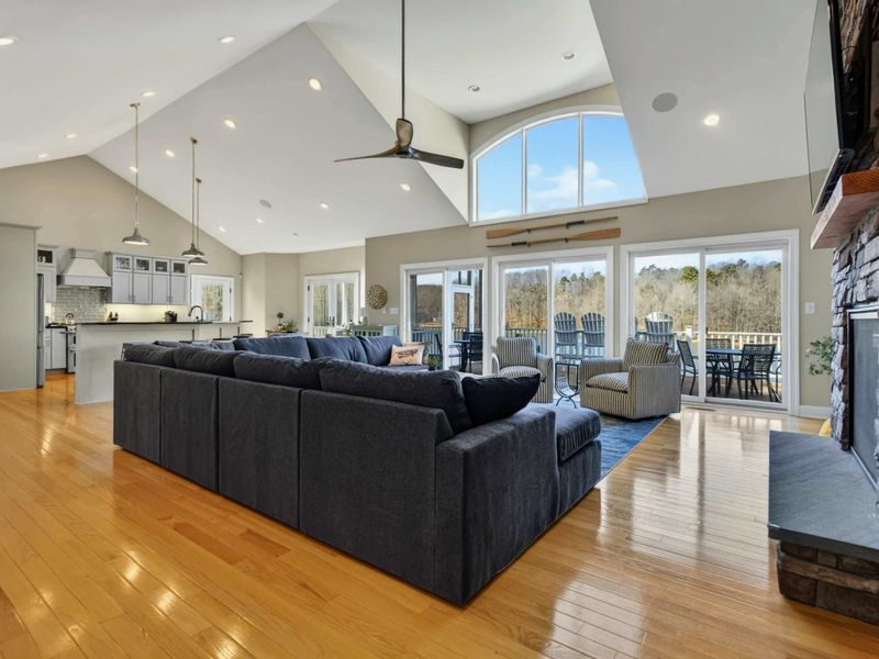 Great Room - Navy blue sectional and striped accent chairs beneath soaring vaulted ceilings with arched window.