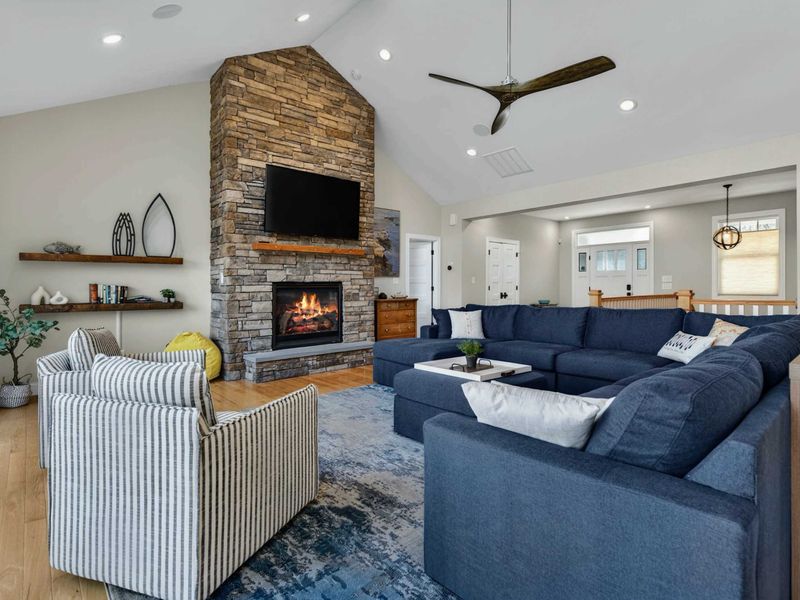 Great Room - Wider view captures the stone fireplace, navy sectional, and open flow to the entry and kitchen.