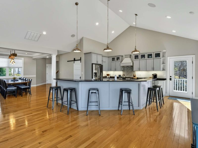 Kitchen and Dining - Full view of the island, barn door pantry, and reclaimed wood chandelier over the dining table.