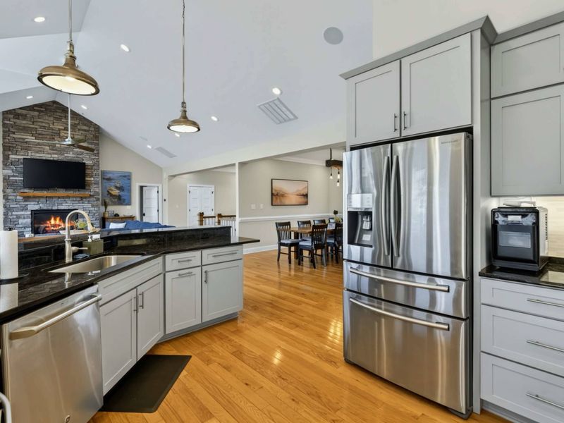 Kitchen - Stainless steel French door refrigerator and gray cabinetry with the dining area visible beyond.