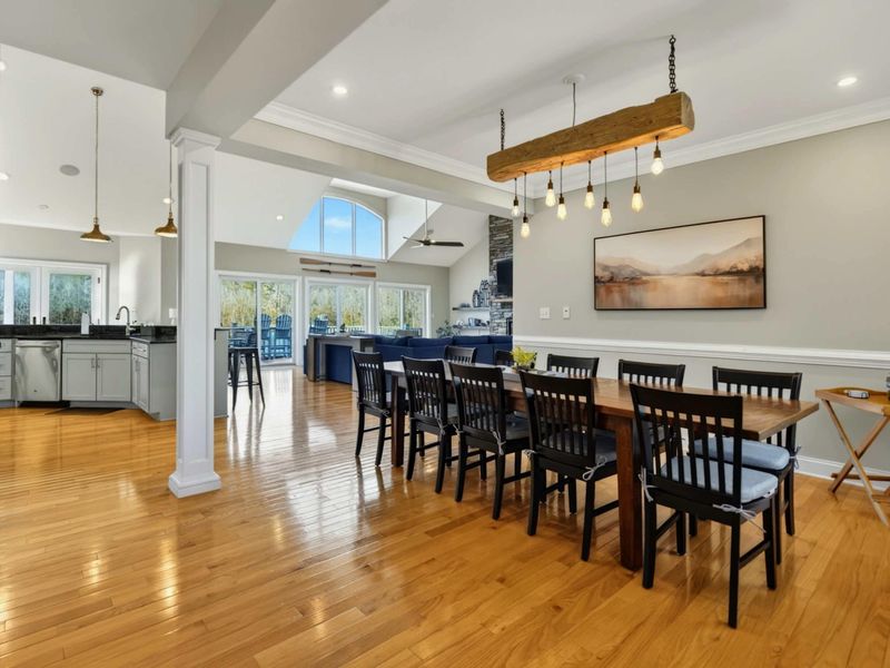 Dining Area - Long farmhouse table with seating for twelve beneath a reclaimed wood beam chandelier.