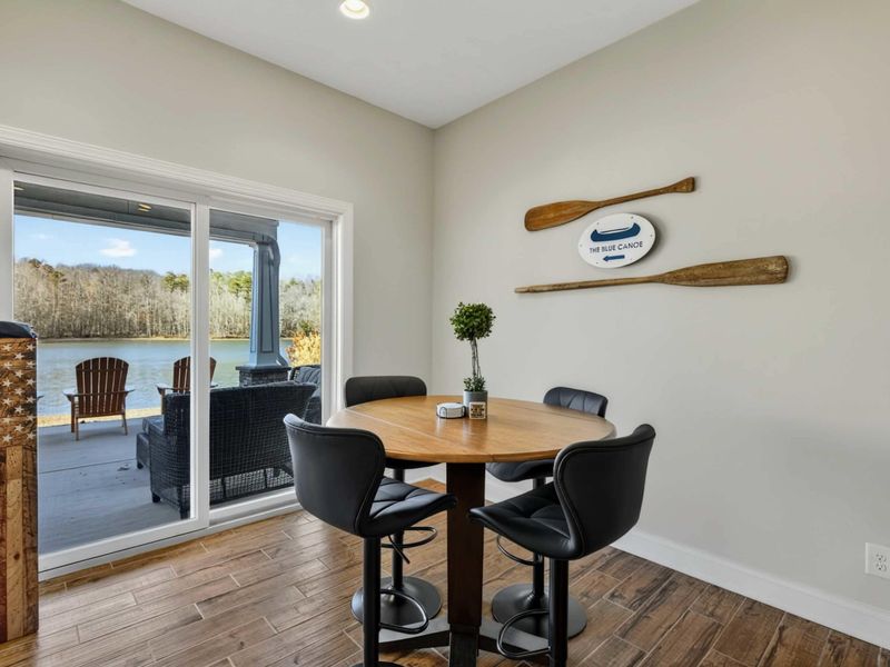 Dining Nook - Pub-height table with The Blue Canoe sign and paddle decor beside the patio slider.