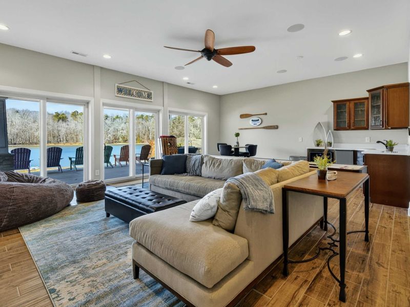 Lower Level Family Room - Spacious living area with sectional, oversized ottoman, and lake view windows leading to the patio.