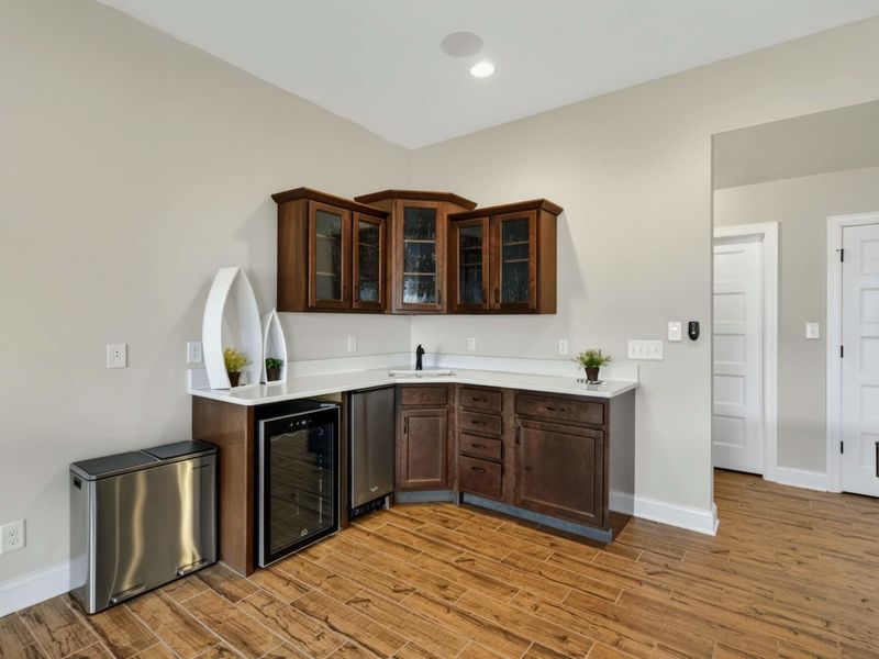 Wet Bar - Dark wood cabinetry with wine cooler, ice maker, and sink for easy entertaining.