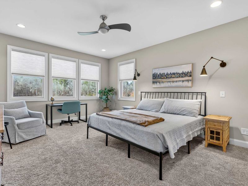 Primary Suite - King bed with iron frame, lake-inspired artwork, reading sconces, and a dedicated workspace.