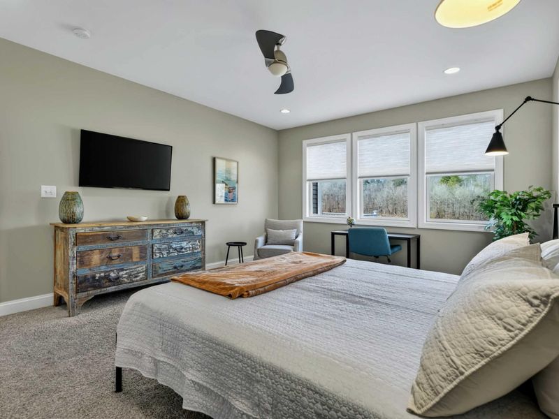 Primary Suite - Wall-mounted TV on a reclaimed wood dresser with a cozy sitting and desk area.