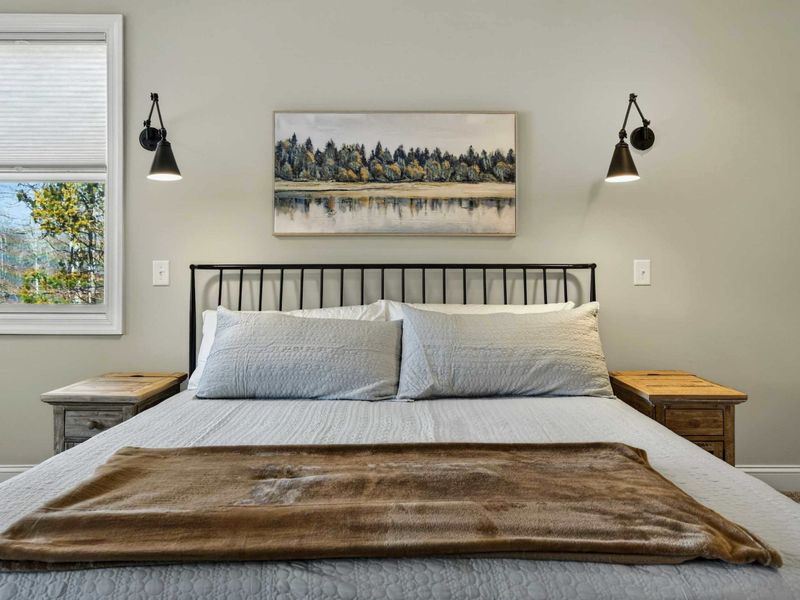 Primary Suite - Iron headboard, crisp linens, and lake reflection art create a serene retreat.