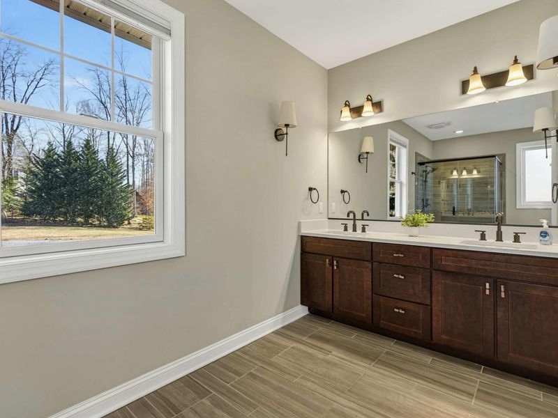 Primary Bathroom - Vanity side view with natural light from a large window overlooking the yard.