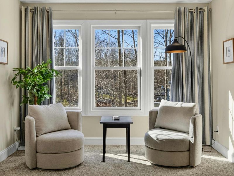 Bedroom 2 - Reading nook with two accent chairs and floor lamp beside large windows.