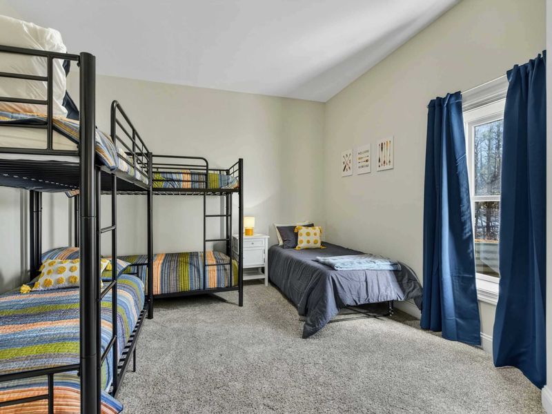 Bunk Room - Two bunk bed sets and a twin bed with colorful striped bedding, perfect for kids.