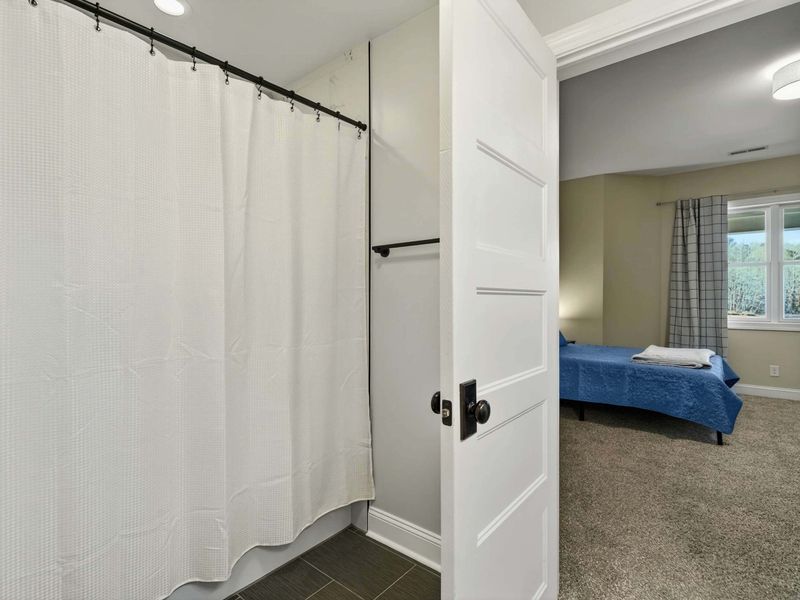 Bathroom - Shower and tub with curtain, conveniently connecting to the adjacent bedroom.