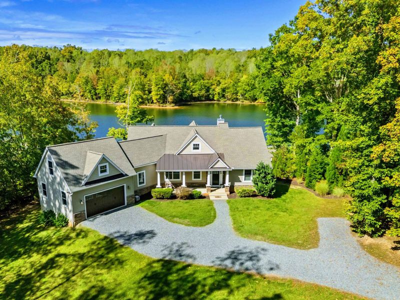 Aerial View - The home's front and side from above, nestled among trees with the lake just beyond.