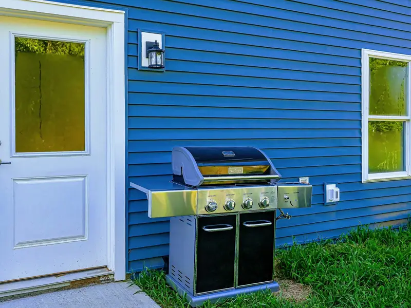 Outdoor Dining - Stainless steel four-burner gas grill stationed by the side entry, perfect for cookouts with your crew.