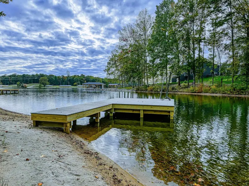 Dock - Wood platform dock with a sandy beach shoreline and sweeping lake views framed by fall foliage.