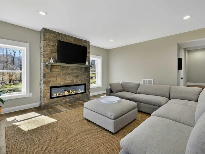 Lower Level Lounge - A large sectional, stone fireplace, and mounted TV create a cozy second living room downstairs.