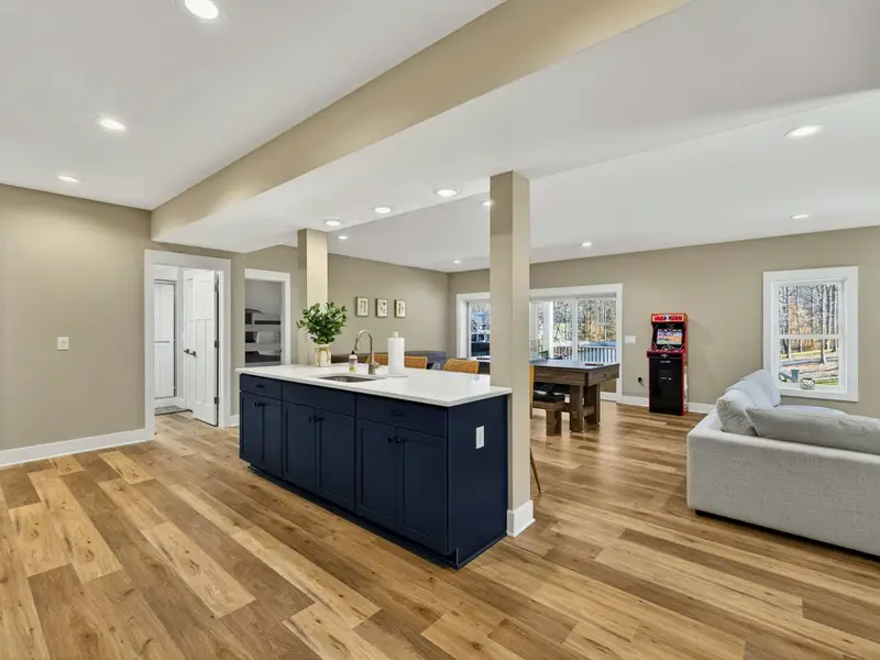 Game Room Layout - The open lower level connects the navy kitchen island, bar seating, and game area all in one space.