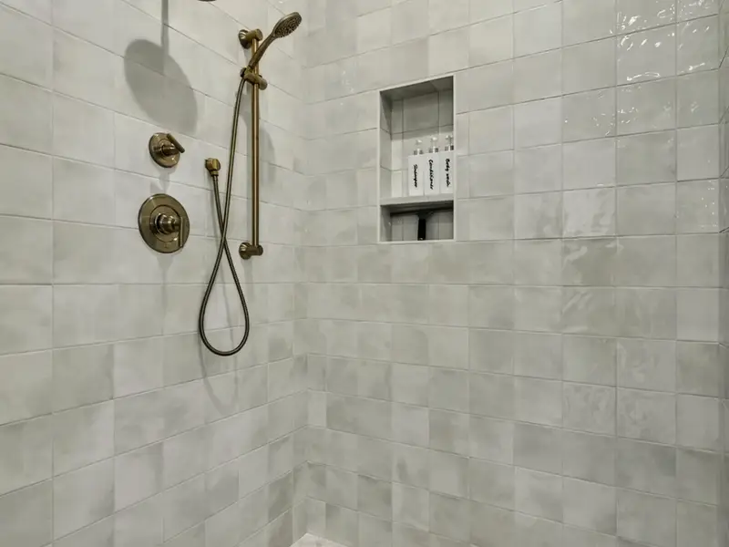 Shower Detail - Brass fixtures and a built-in niche inside the primary bath shower.