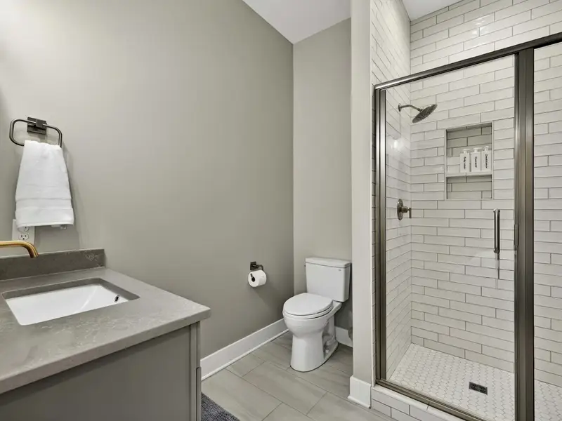 Ensuite Bathroom - A walk-in shower with subway tile, vanity with brass fixtures, and clean modern finishes.