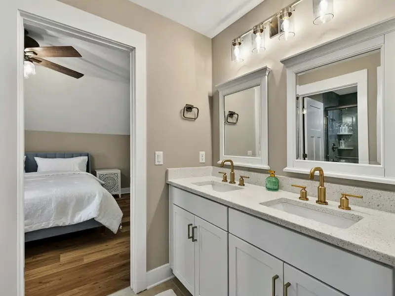 Shared Bath Vanity - Double mirrors, brass fixtures, and a clean countertop in the shared upper bath.