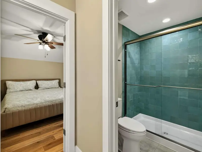 Shared Bath - The full shared bath with a teal-tiled walk-in shower and access to the upper bedroom.
