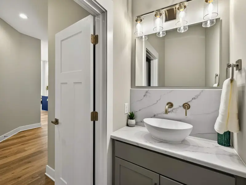 Powder Room - A vessel sink with marble backsplash and brass wall-mount faucet in the main-level half bath.