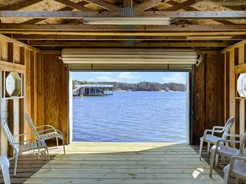 Boathouse View - Chairs flank the open bay door, framing a postcard view of the lake from inside the converted boathouse.