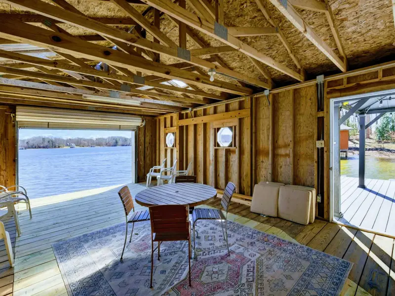 Boathouse Lounge - A couch and table inside the boathouse make this a cozy retreat with porthole windows and lake views through the open bay door.