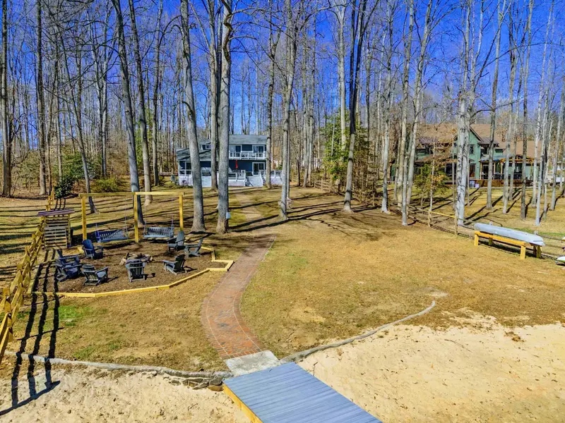 Yard and Grounds - A brick path winds from the dock through the fire pit area, past bench swings and sandy beach, up toward the house.