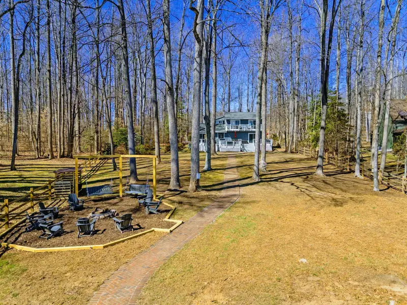 Backyard - The expansive yard connects the house to the fire pit and dock area, with tall trees providing shade and privacy.