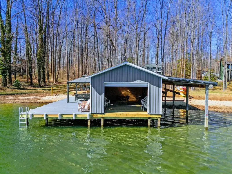 Boathouse Aerial - The boathouse garage door opens to the lake, with colorful kayaks stored on the roof rack for easy launch.