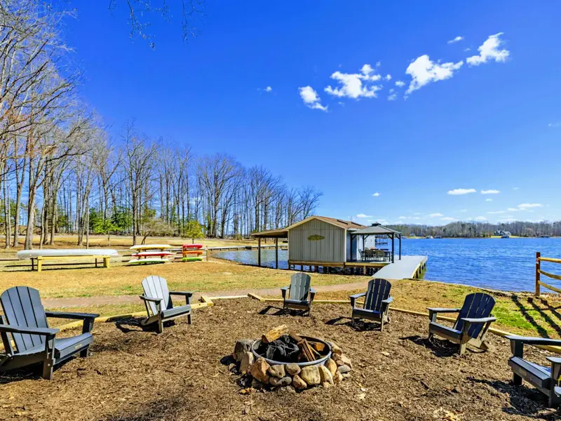 Lakeside Fire Pit - A circle of Adirondack chairs surrounds the fire pit overlooking the lake, with the boathouse and dock just steps away.