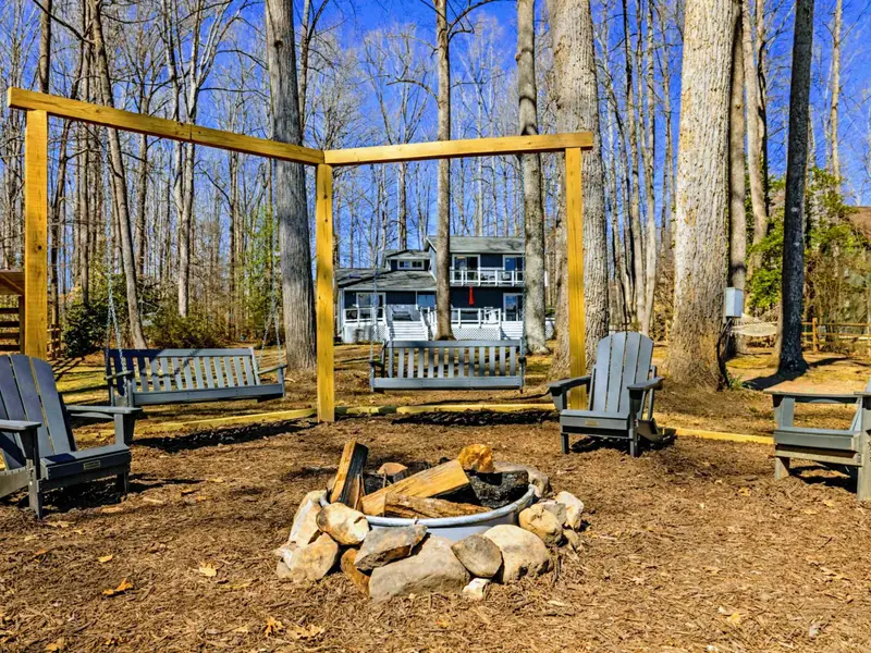 Evening Gathering Spot - The bench swings frame the fire pit area, with the house and wooded lot creating a private, camp-like setting.