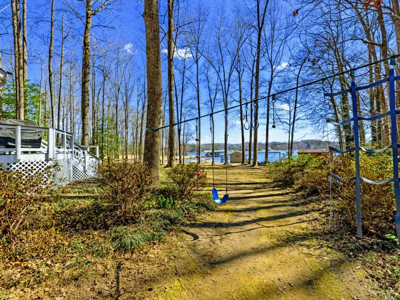 Wooded Trail - A path through the trees connects the ninja course to the lakefront, blending adventure with the natural beauty of the lot.