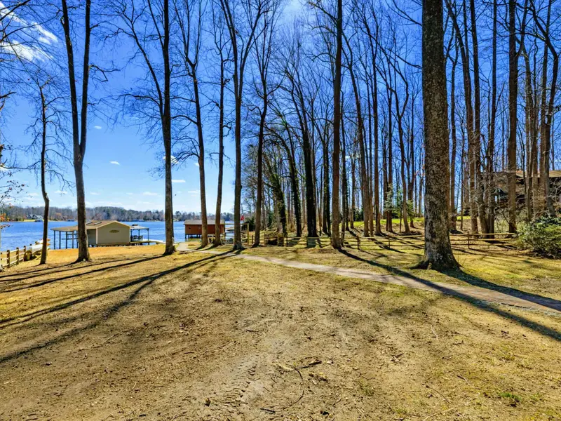 Wooded Lot - Tall trees frame the view from the house down to the boathouse and lake, with the long, private lot stretching all the way to the water.