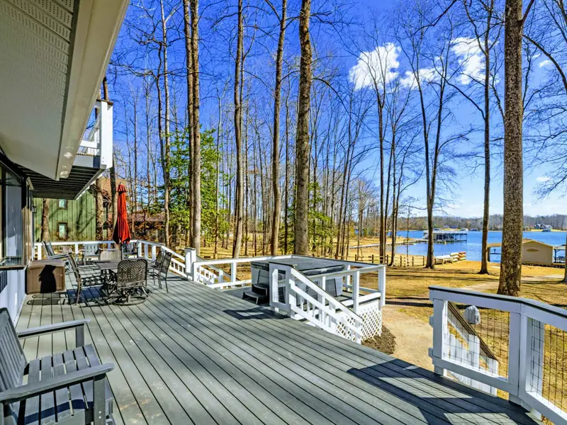 Main Deck - A dining table and rocking chairs sit on the main deck, where the lake shimmers through the trees just beyond the railing.