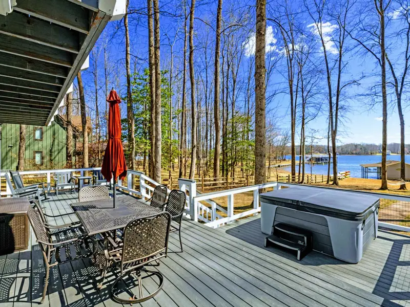 Outdoor Dining - The main deck dining area with a red umbrella sits just above the hot tub, offering lake views and a natural gathering spot for meals outside.