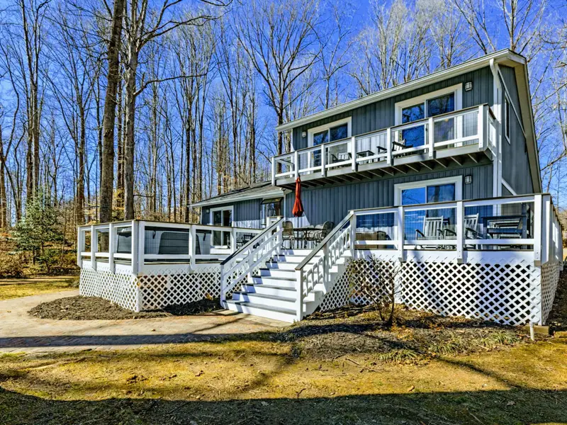 Side Exterior - Two levels of decking with white railings and wide stairs offer easy flow between the main floor, lower level, and yard.