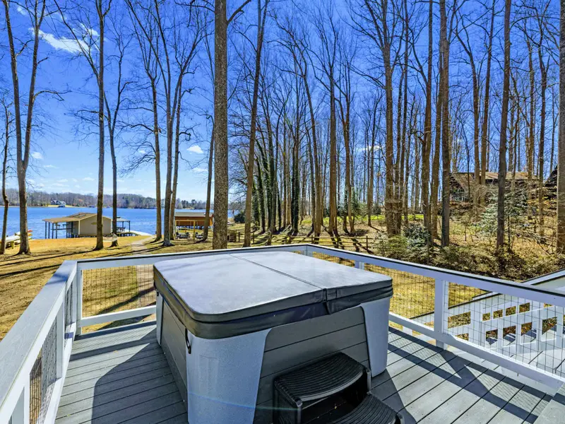 Hot Tub View - Looking out over the hot tub from the upper deck, with the lake and boathouse visible below through the trees.